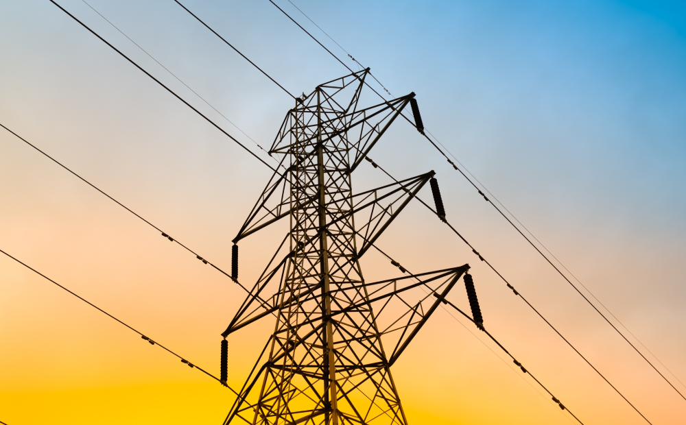 High-voltage transmission tower with power lines at sunset, symbolizing energy infrastructure.