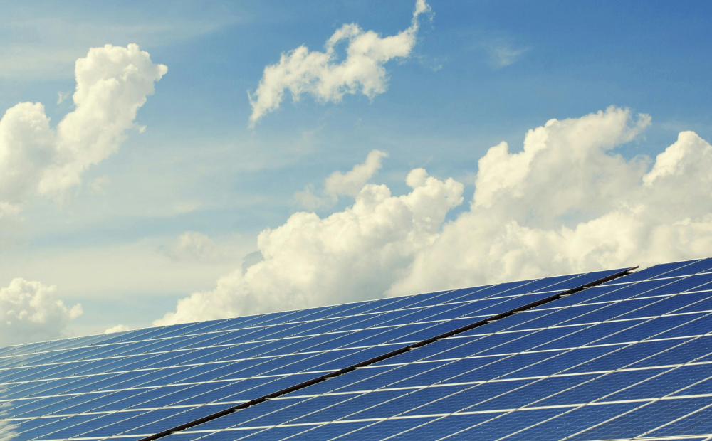 Solar panel array under a bright blue sky with scattered clouds, representing clean energy production.