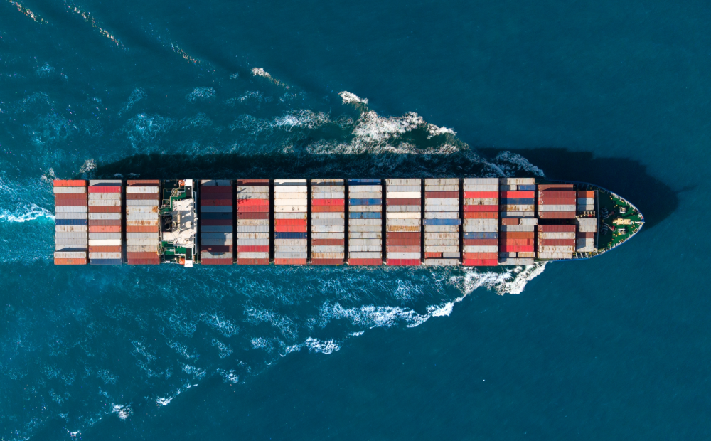 Aerial view of a large cargo ship transporting colorful shipping containers across the ocean.